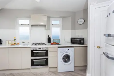 a kitchen with a washing machine and a washer at Pelorus Cottage in St Merryn