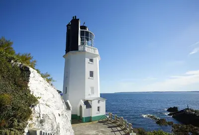 a lighthouse sitting on the side of the ocean at Sally Port Cottage in Saint Mawes