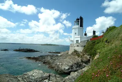 a lighthouse on a cliff next to the ocean at Sally Port Cottage in Saint Mawes