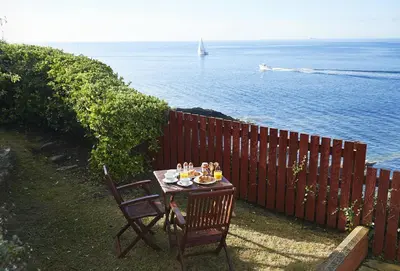 a table with food on it next to the ocean at Sally Port Cottage in Saint Mawes
