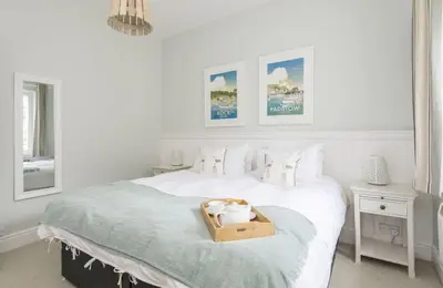 a white bedroom with a bed with a wooden box on it at Sally Port Cottage in Saint Mawes