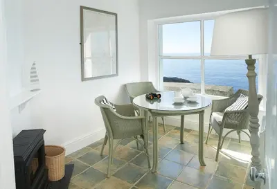 a dining room with a table and chairs and a window at Sally Port Cottage in Saint Mawes