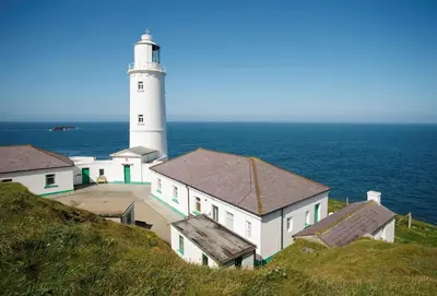 a lighthouse on a hill next to the ocean at Verity Cottage in St Merryn