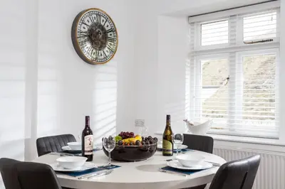 a dining room table with a bowl of fruit and wine bottles at Verity Cottage in St Merryn