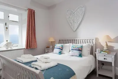 a bedroom with a white bed with towels on it at Verity Cottage in St Merryn