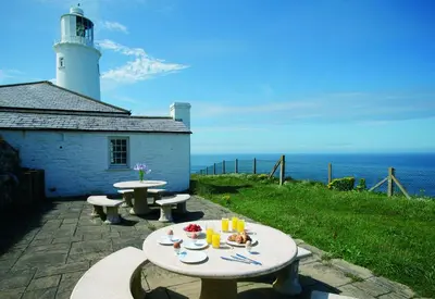 a table with two benches and a lighthouse at Verity Cottage in St Merryn