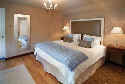 a bedroom with a large bed and a mirror at Spring Water Barn in Helston