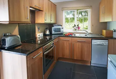 a kitchen with wooden cabinets and a sink and a microwave at Spring Water Barn in Helston