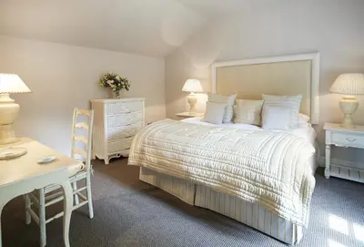 a bedroom with a bed and a table and a desk at Mews Cottage in Helston