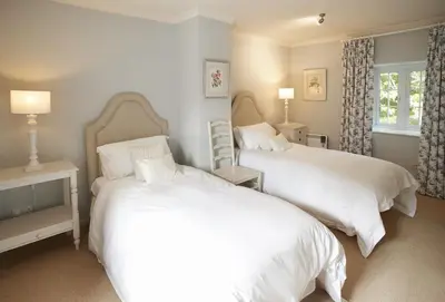 a bedroom with two beds and a window at Mews Cottage in Helston