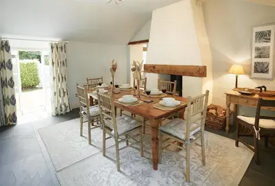 a dining room with a wooden table and chairs at Mews Cottage in Helston