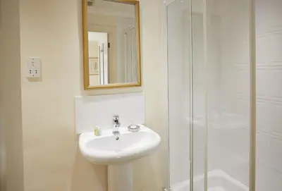 a white bathroom with a sink and a shower at Mews Cottage in Helston