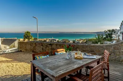 a wooden table with chairs and a view of the ocean at 2 Bed in St. Ives oc-1seab in St Ives