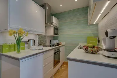 a kitchen with white cabinets and a vase of flowers on the counter at 1 Bed in St. Ives oc-aqua19 in St Ives