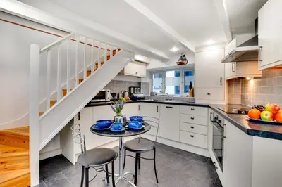 a kitchen with white cabinets and a small table with chairs at 3 Bed in St Ives oc-bail05 in St Ives