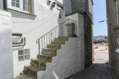 a stairway leading up to a white building with a beach at 1 Bed in St Ives oc-chyr2 in St Ives
