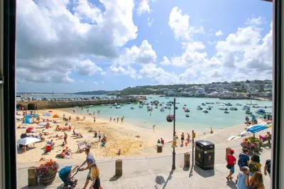 a beach with a bunch of people in the water at 1 Bed in St Ives oc-chyr2 in St Ives