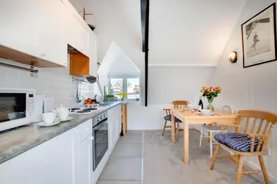 a kitchen with white cabinets and a wooden table at 1 Bed in St. Ives oc-cp5 in St Ives