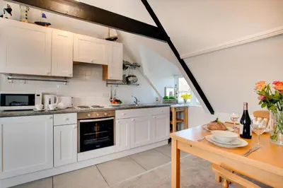 a kitchen with white cabinets and a wooden table at 1 Bed in St. Ives oc-cp5 in St Ives