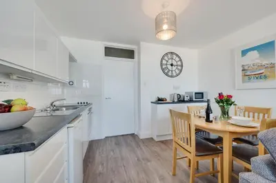 a kitchen with white cabinets and a table with a bowl of fruit at 1 Bed in St Ives oc-cwn014 in St Ives