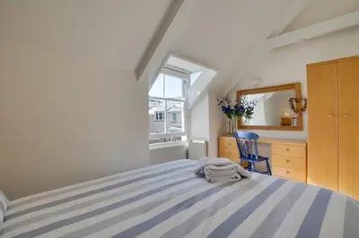 a bedroom with a bed with a blue chair and a window at 1 Bed in St Ives oc-dgy028 in St Ives