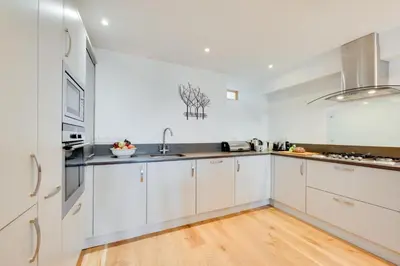 a white kitchen with white cabinets and a wooden floor at 2 Bed in St Ives oc-f1meor in St Ives