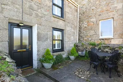 a stone house with a black door and a table and chairs at 1 Bed in St. Ives oc-farr in St Ives