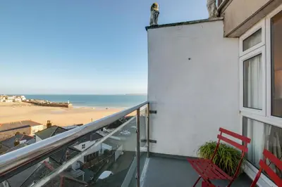 a balcony with two red chairs and a view of the beach at 2 Bed in St Ives oc-fern42 in St Ives