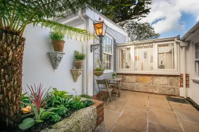 a home with a patio with a table and plants at Hideaway Tremayne in St Ives