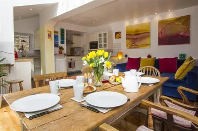 a dining room table with white plates and flowers on it at Hideaway Tremayne in St Ives