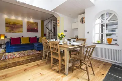 a dining room with a table and chairs and a couch at Hideaway Tremayne in St Ives