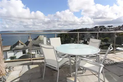 a table and chairs on a balcony with a view of the ocean at 2 Bed in St Ives oc-holm in Carbis Bay