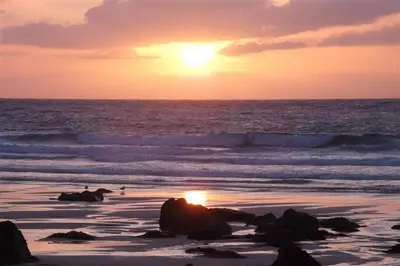 a sunset on a beach with the ocean and waves at 1 Bed in St Ives oc-nic01 in St Ives