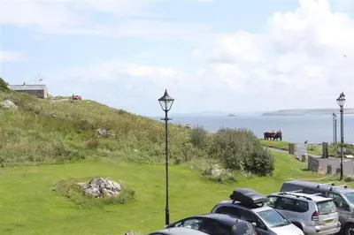 a parking lot with cars parked on a hill next to the ocean at 1 Bed in St Ives oc-nic48 in St Ives