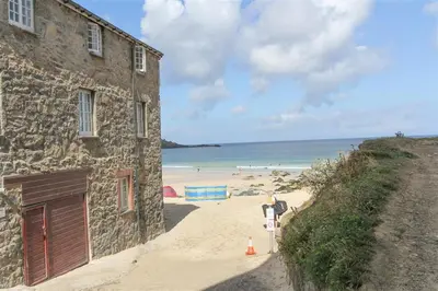 a building next to a beach with people in the water at 1 Bed in St Ives oc-nic049 in St Ives