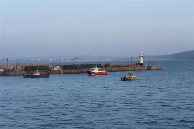 a group of boats in the water with a lighthouse at 1 Bed in St Ives oc-quayst in St Ives