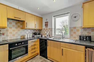 a kitchen with wooden cabinets and a clock on the wall at 2 Bed in Carbis Bay oc-t27418 in Carbis Bay