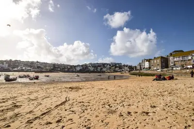 a beach with people sitting on the sand at 2 Bed in St Ives oc-tee009 in St Ives