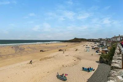 a beach with people on the sand and the ocean at 3 Bed in St. Ives oc-trecar in St Ives