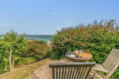 a chair and a toy train sitting next to the ocean at 3 Bed in St. Ives oc-trecar in St Ives