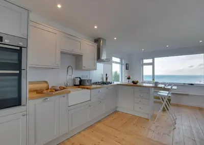 a kitchen with white cabinets and a view of the ocean at 3 Bed in St. Ives oc-trecar in St Ives