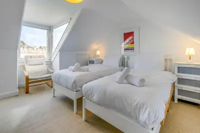 a bedroom with two beds and a chair and a window at 3 Bed in St Ives oc-twtc11 in St Ives