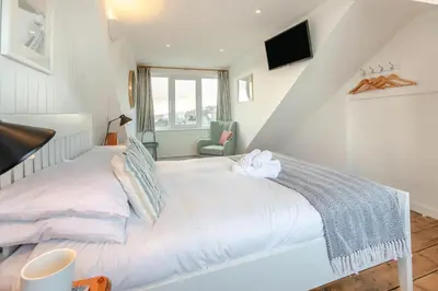 a white bedroom with a bed and a chair at 3 Bed in St Ives oc-vgn28 in St Ives