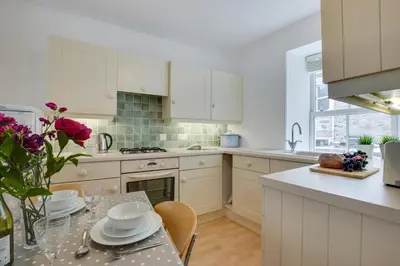 a kitchen with white cabinets and a table with dishes on it at 2 Bed in St Ives oc-wyp026 in St Ives