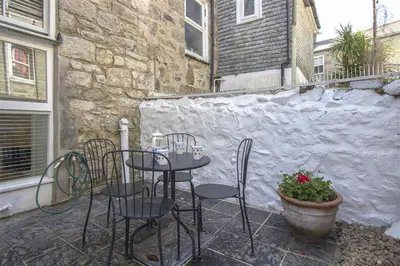 a table and chairs on a patio with a stone wall at 2 Bed in St Ives oc-wyp026 in St Ives