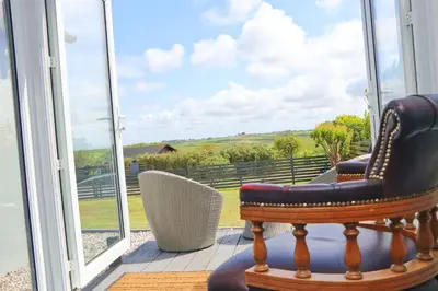 a chair sitting in front of a window on a porch at Coastal retreat surrounded by open countryside in Saint Ervan
