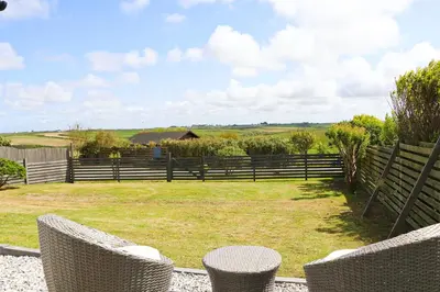 a garden with two chairs and a fence at Coastal retreat surrounded by open countryside in Saint Ervan