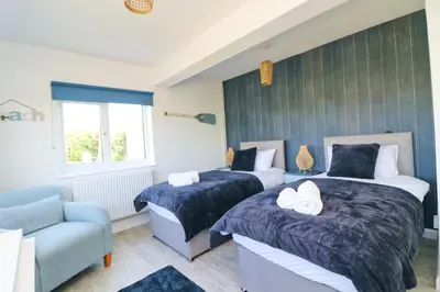 two beds in a room with a couch and a chair at Coastal retreat surrounded by open countryside in Saint Ervan