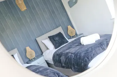 a mirror reflection of a bedroom with two beds at Coastal retreat surrounded by open countryside in Saint Ervan