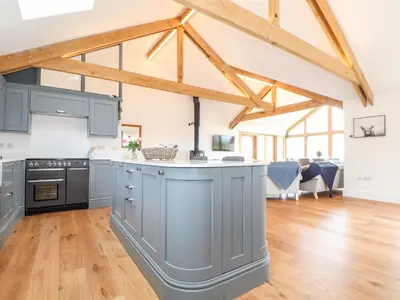 an open kitchen with blue cabinets and wooden floors at Trevilges Cottage in Helston